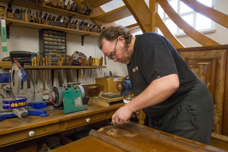 Ébéniste en pleine restauration de meuble ancien à Kaysersberg